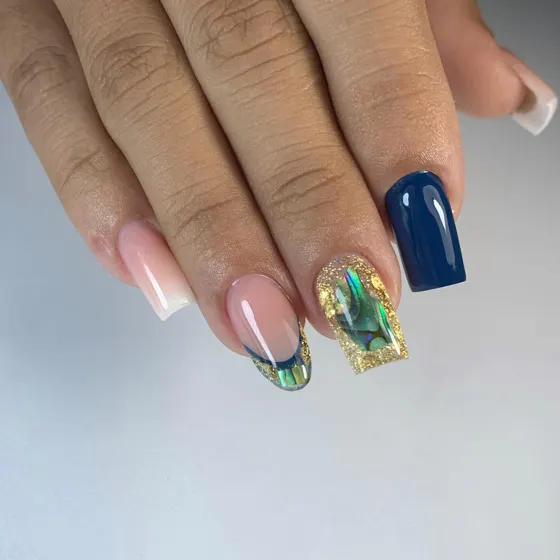 Uñas azules con detalles dorados y concha